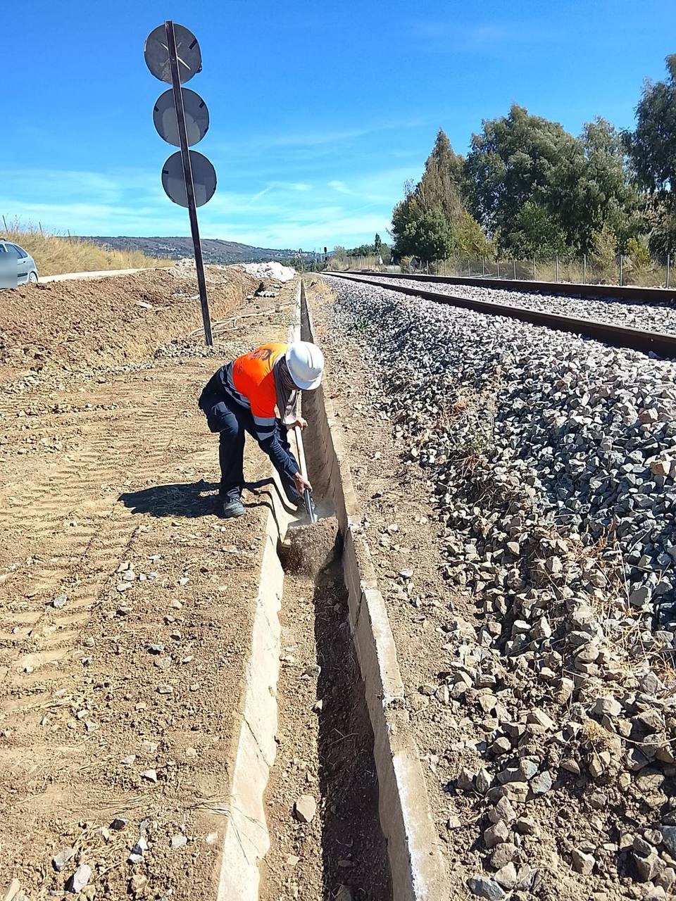 Operario de Cimentaworks con casco y ropa de alta visibilidad retirando material del interior de la cuneta con pala