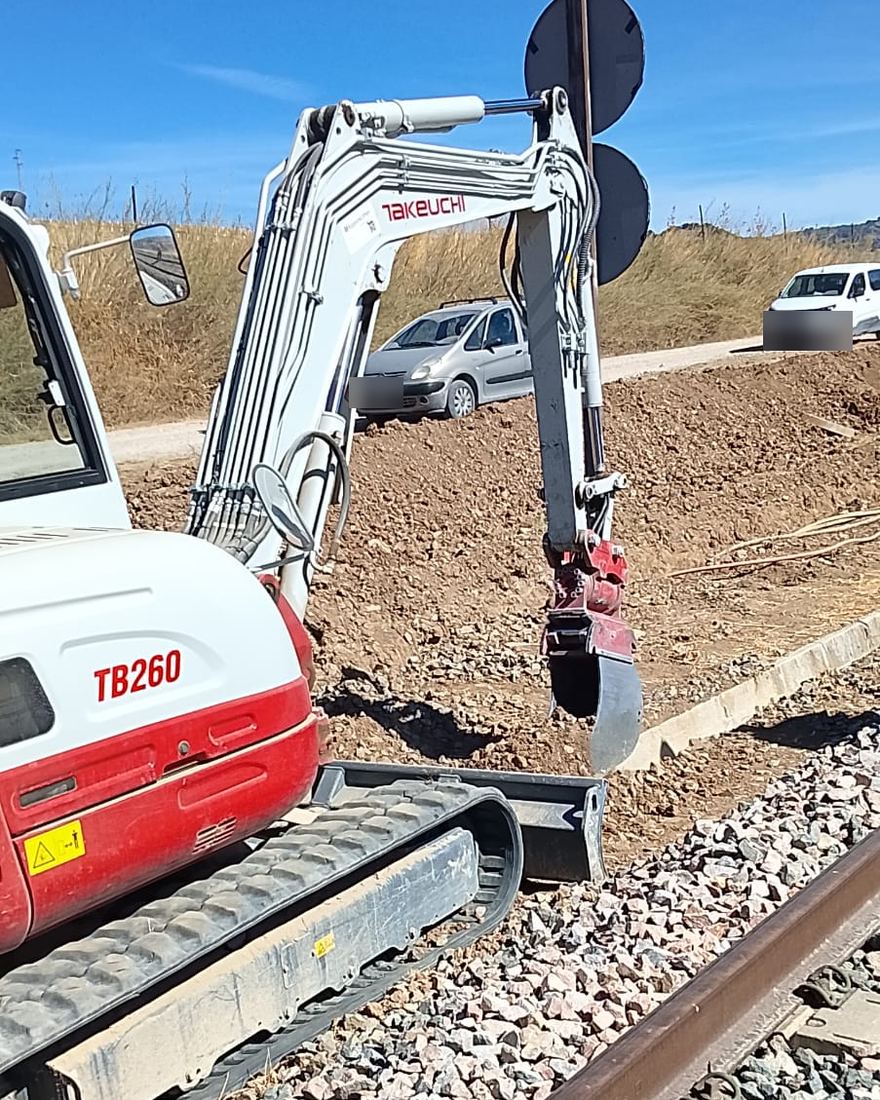Miniexcavadora de cadenas perfilando el terreno en el margen de la plataforma ferroviaria, junto al carril
